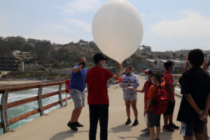 students launching weather balloon on Scripps Pier