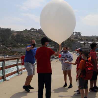 students launching weather balloon on Scripps Pier